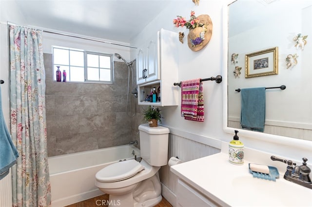 bathroom with vanity, wainscoting, shower / bath combination with curtain, and toilet