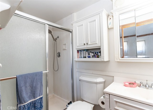 bathroom with toilet, a shower stall, and vanity