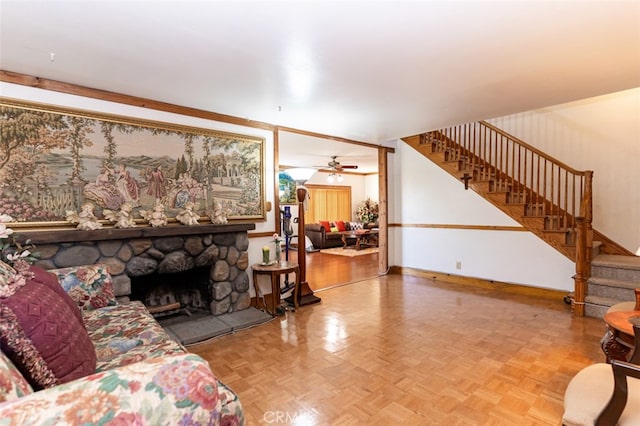 living room featuring stairs, baseboards, and a stone fireplace