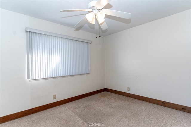 spare room with a ceiling fan, light colored carpet, and baseboards