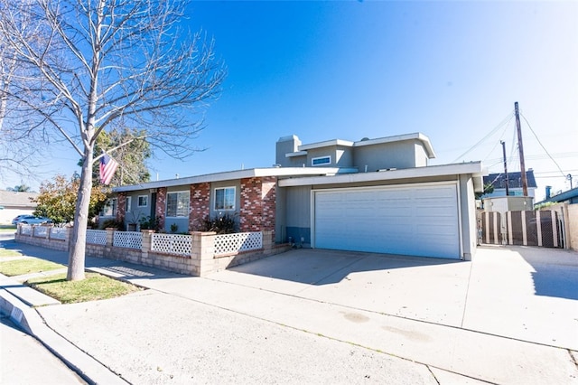 view of front facade featuring concrete driveway, fence, and an attached garage