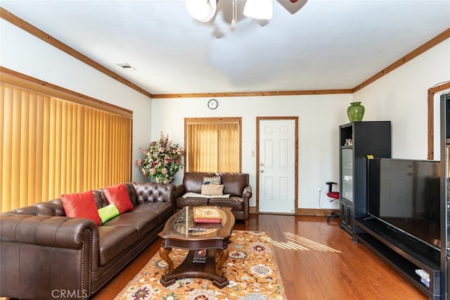 living room with ornamental molding, wood finished floors, visible vents, and baseboards