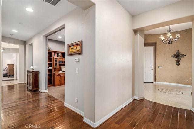 hallway with a chandelier, dark wood-style flooring, and baseboards