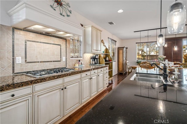 kitchen featuring pendant lighting, dark wood-style flooring, tasteful backsplash, visible vents, and a sink