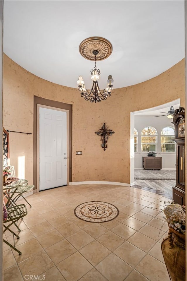 unfurnished dining area with ceiling fan with notable chandelier, baseboards, and light tile patterned floors