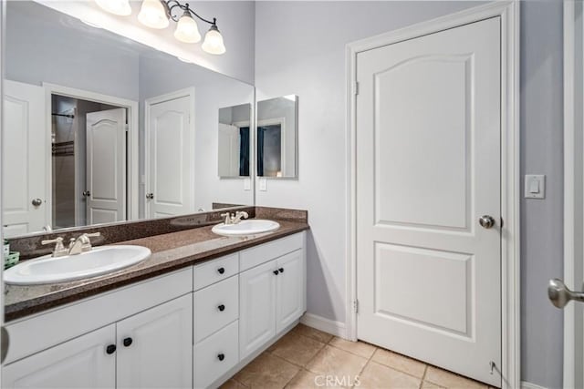 full bath with double vanity, tile patterned flooring, baseboards, and a sink