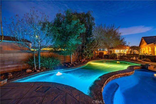 view of swimming pool with a fenced backyard and a pool with connected hot tub