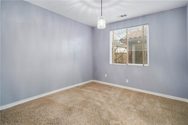 carpeted spare room featuring a chandelier, visible vents, and baseboards