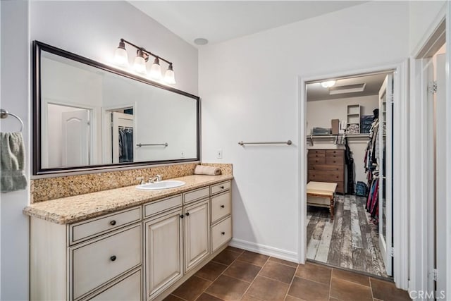 full bathroom with tile patterned flooring, a spacious closet, baseboards, and vanity