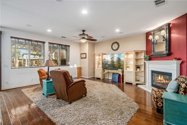 living area with dark wood-style floors, recessed lighting, visible vents, and a glass covered fireplace