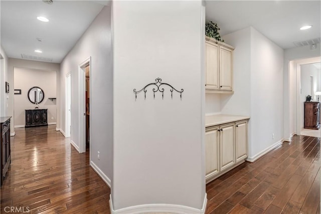 hall with dark wood-style floors, recessed lighting, visible vents, and baseboards