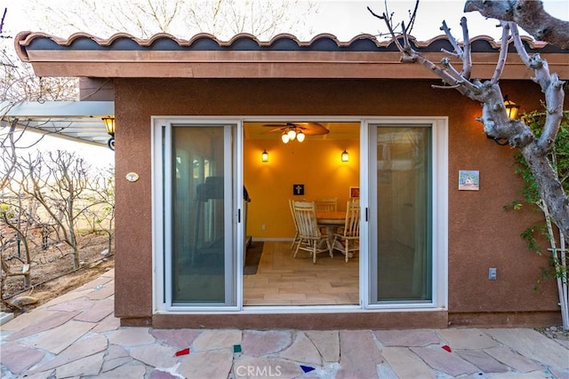 view of exterior entry with a patio and stucco siding