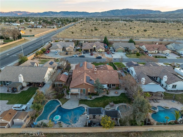 aerial view at dusk featuring a mountain view and a residential view