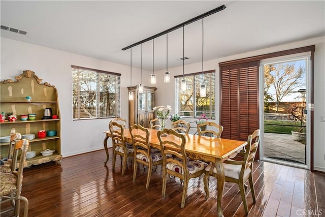 dining space with dark wood-style flooring, visible vents, plenty of natural light, and baseboards