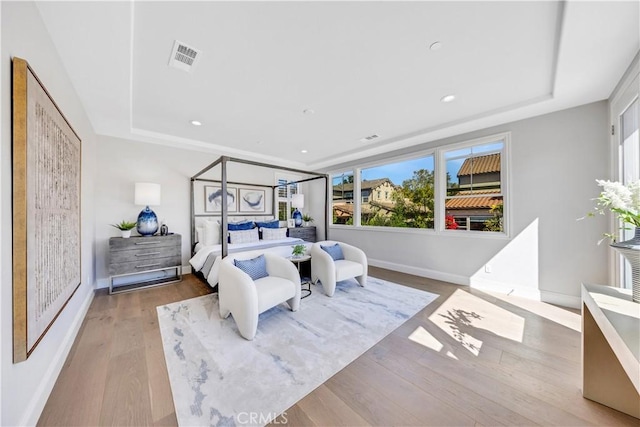 bedroom featuring light wood-type flooring, baseboards, a raised ceiling, and recessed lighting