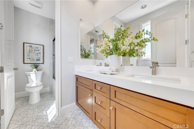 full bath featuring toilet, double vanity, bath / shower combo with glass door, and a sink