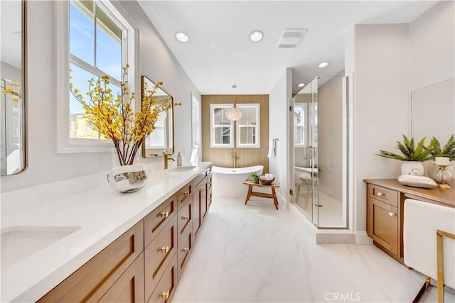 bathroom featuring marble finish floor, double vanity, a soaking tub, a sink, and a shower stall