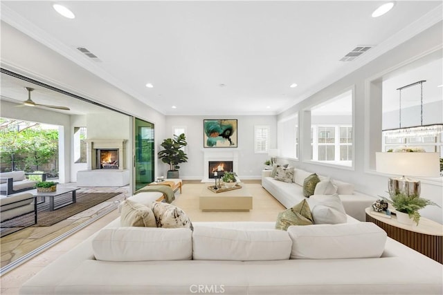 living area featuring ornamental molding, recessed lighting, visible vents, and a lit fireplace