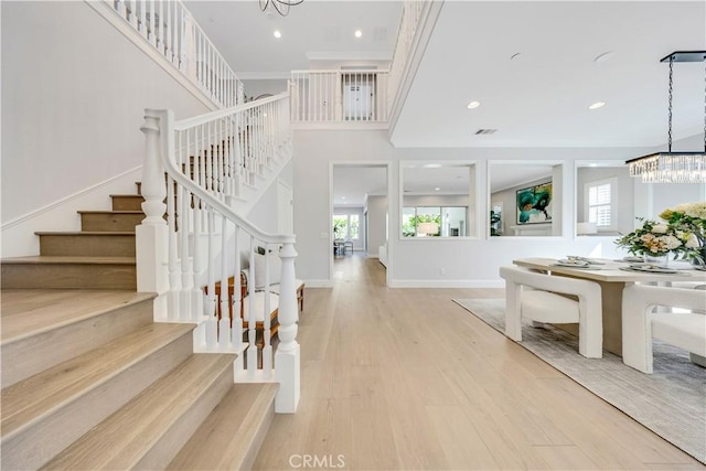 foyer with a healthy amount of sunlight, light wood-style flooring, baseboards, and a chandelier