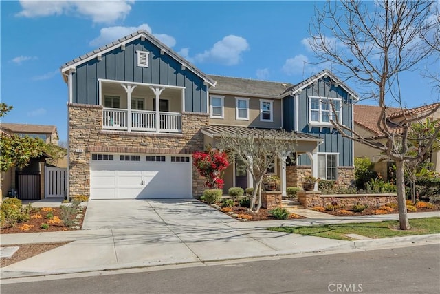 view of front of home with driveway, board and batten siding, stone siding, and a balcony