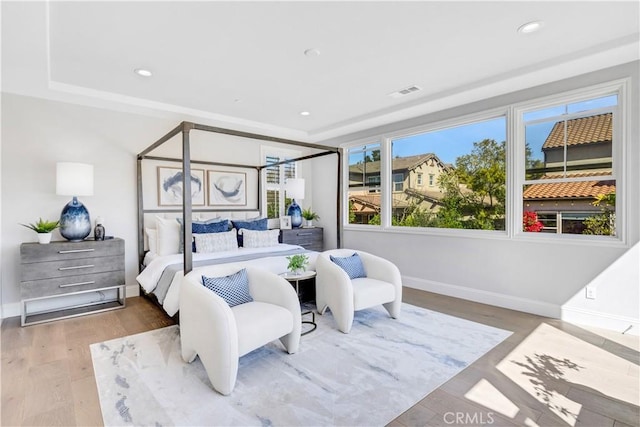 bedroom with baseboards, wood finished floors, visible vents, and recessed lighting