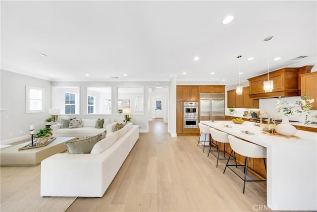 living room featuring light wood-type flooring, visible vents, crown molding, and recessed lighting