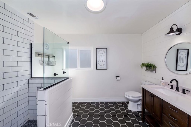 bathroom with a walk in shower, toilet, vanity, visible vents, and baseboards