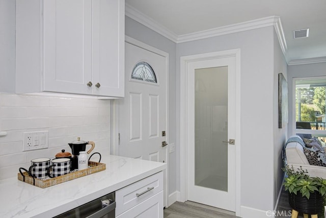 interior space with light stone counters, white cabinets, ornamental molding, and light wood-style flooring