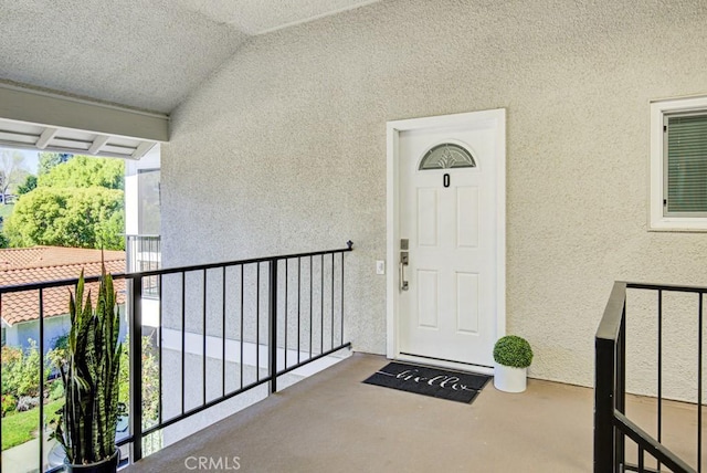 entrance to property featuring a balcony and stucco siding