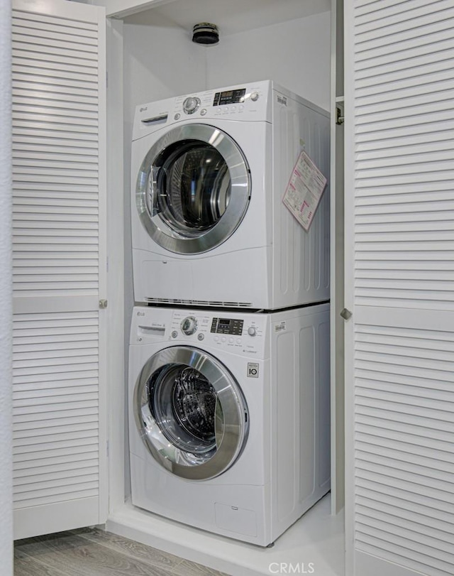 washroom featuring laundry area, light wood finished floors, and stacked washer / drying machine