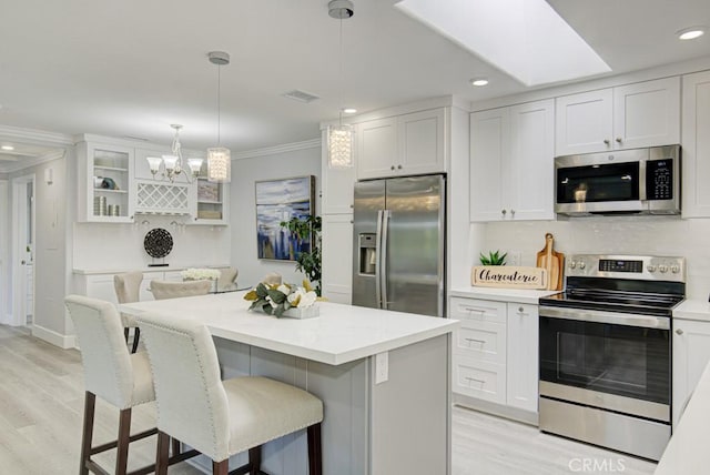 kitchen featuring appliances with stainless steel finishes, white cabinets, light countertops, and glass insert cabinets