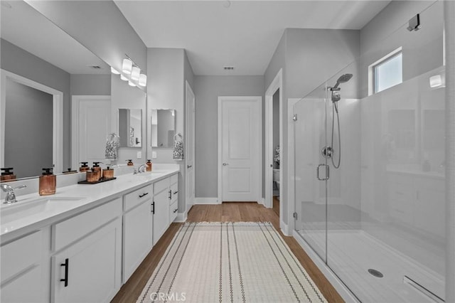 bathroom with a stall shower, a sink, and wood finished floors