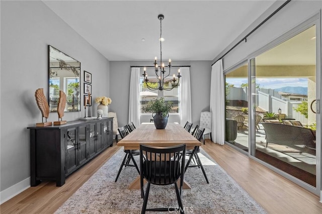 dining area with baseboards, light wood finished floors, and a notable chandelier