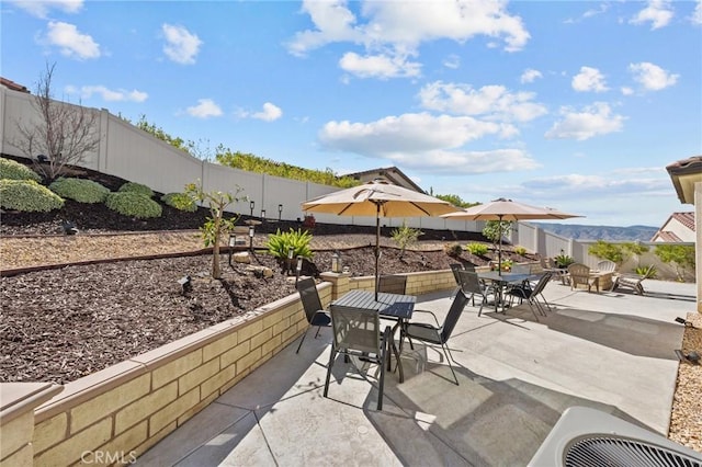 view of patio / terrace featuring outdoor dining space, a fenced backyard, a mountain view, and cooling unit