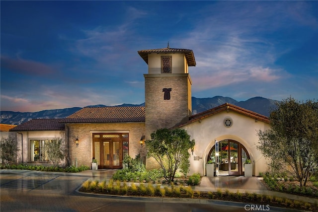 mediterranean / spanish house featuring french doors, a mountain view, a tiled roof, and stucco siding