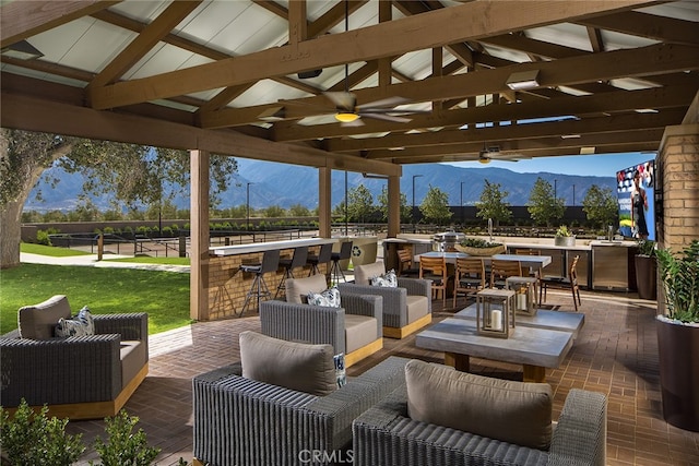 view of patio with outdoor dry bar, ceiling fan, an outdoor hangout area, and a mountain view