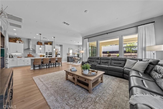 living room with light wood finished floors, visible vents, and recessed lighting