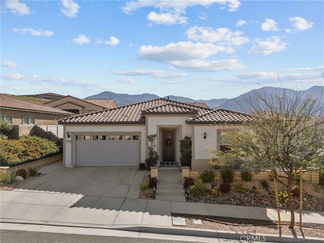 mediterranean / spanish-style home with a garage, driveway, a tile roof, a mountain view, and stucco siding