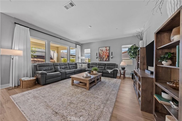 living area featuring light wood-type flooring, visible vents, and baseboards