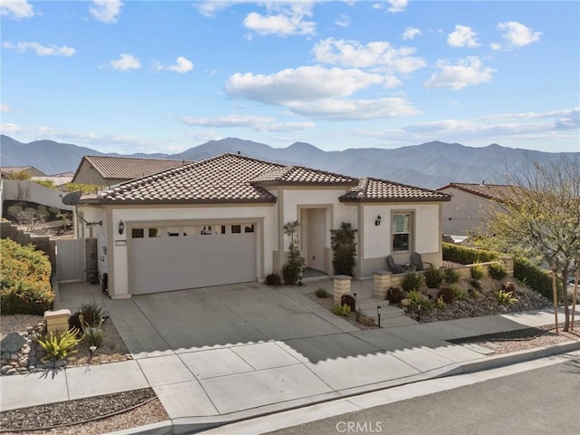 view of front of home featuring concrete driveway, a tile roof, an attached garage, a mountain view, and stucco siding