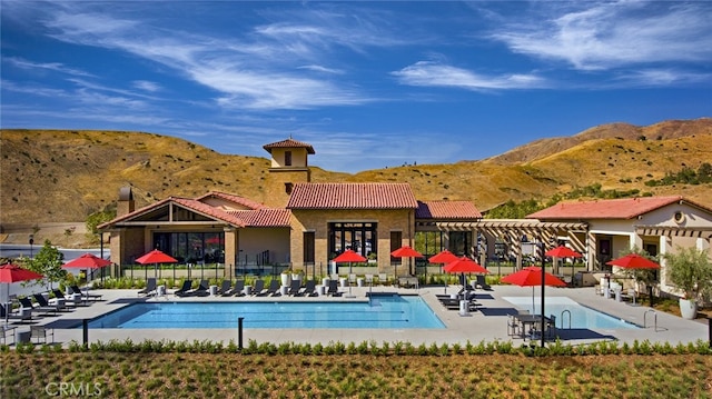 pool featuring a patio area, fence, and a mountain view