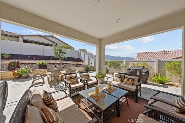 view of patio / terrace with a fenced backyard, a mountain view, an outdoor living space, and grilling area