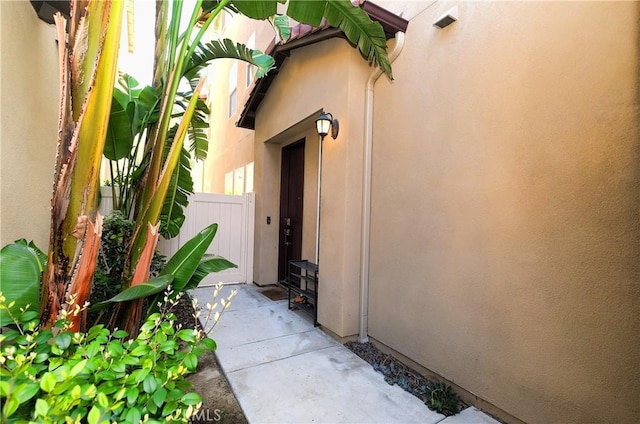 property entrance featuring fence and stucco siding