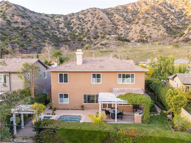 back of house with fence, a tile roof, stucco siding, a chimney, and a patio area