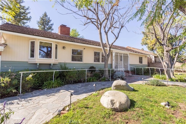 view of front of home with a chimney, fence, and a front yard