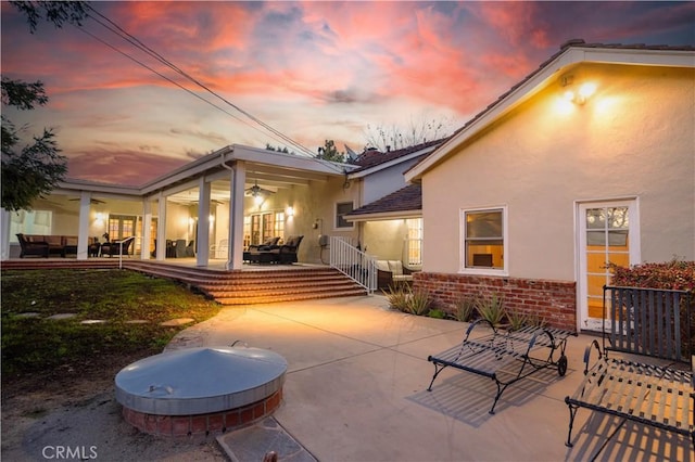 rear view of property with a patio, brick siding, a jacuzzi, and stucco siding