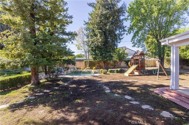 view of yard with a playground, a fenced backyard, and a fenced in pool