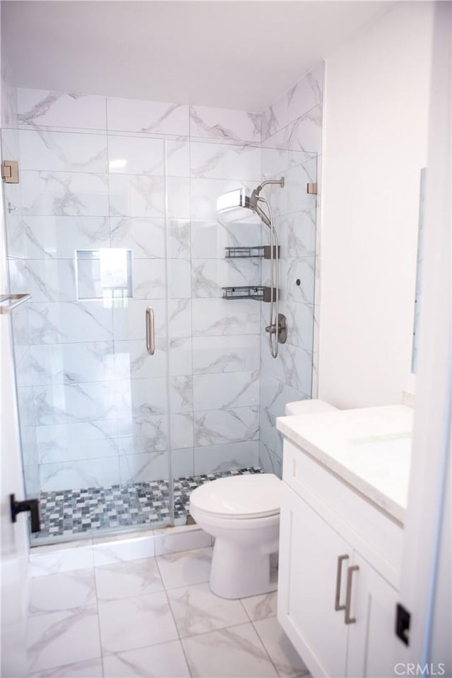 bathroom with toilet, marble finish floor, vanity, and a stall shower