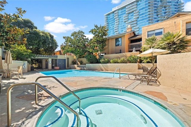 pool with a patio area, a hot tub, and fence