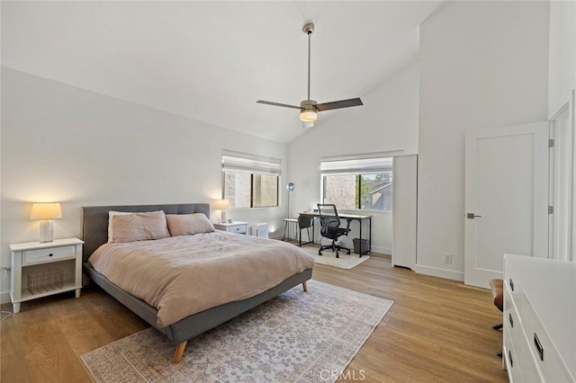 bedroom featuring high vaulted ceiling, light wood-type flooring, baseboards, and a ceiling fan